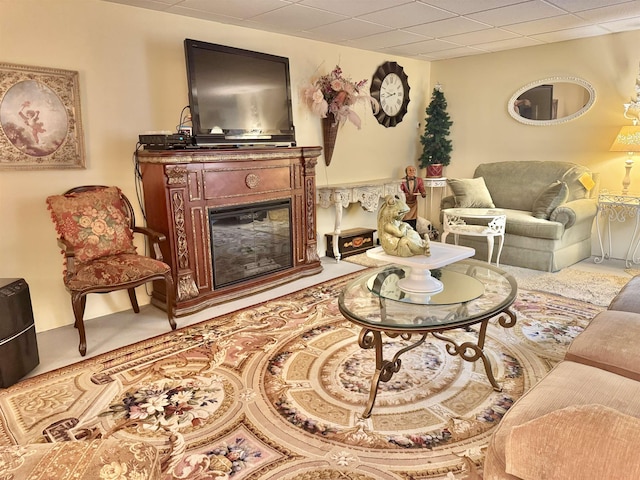 carpeted living area with a paneled ceiling and a glass covered fireplace