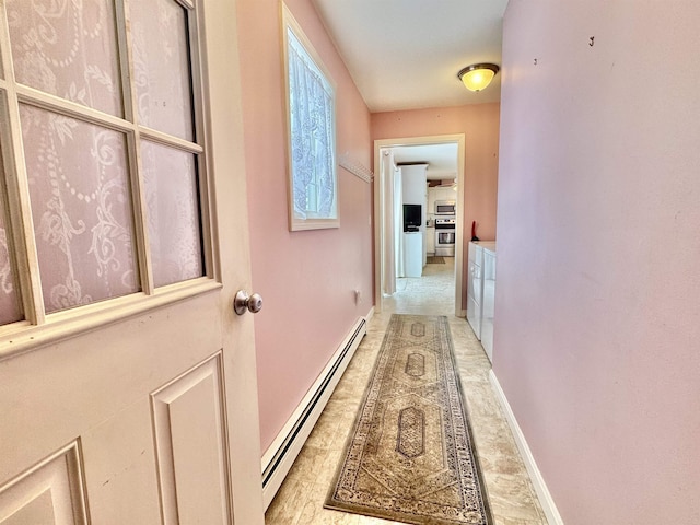 corridor featuring a baseboard heating unit and baseboards