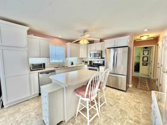 kitchen featuring tasteful backsplash, a kitchen island, light countertops, appliances with stainless steel finishes, and white cabinets