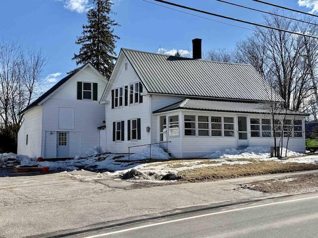 view of front facade with a chimney, metal roof, and a sunroom