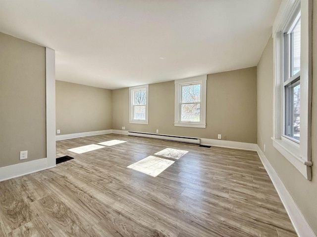 unfurnished room with a baseboard heating unit, baseboards, and wood finished floors