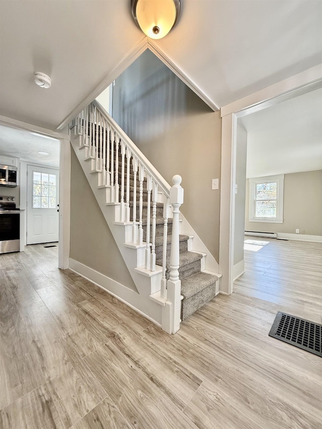 staircase with visible vents, baseboards, a healthy amount of sunlight, and wood finished floors