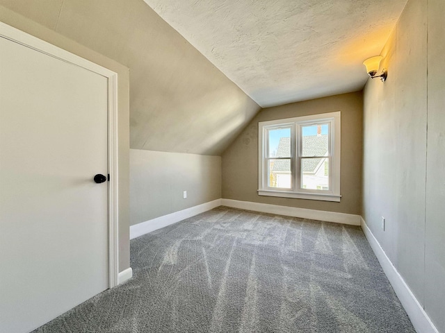 bonus room featuring baseboards, a textured ceiling, carpet, and vaulted ceiling