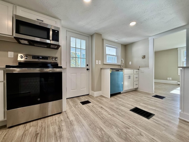 kitchen with a textured ceiling, visible vents, appliances with stainless steel finishes, and light wood-type flooring