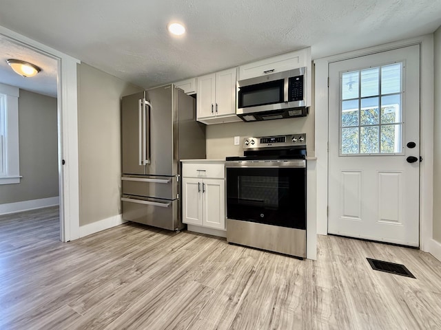 kitchen featuring visible vents, white cabinetry, appliances with stainless steel finishes, and a textured ceiling