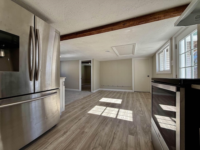 kitchen with beam ceiling, wood finished floors, freestanding refrigerator, and a textured ceiling