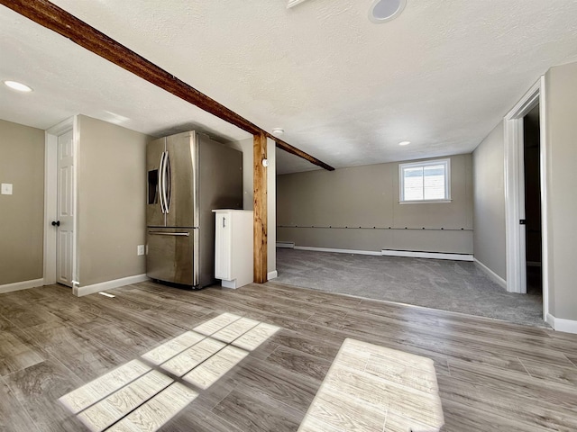 unfurnished living room featuring light wood-style flooring, a textured ceiling, baseboards, and a baseboard radiator