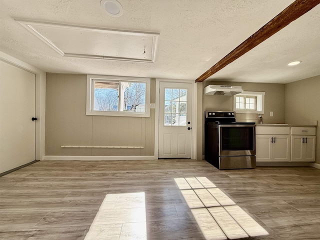 kitchen featuring under cabinet range hood, a textured ceiling, stainless steel range with electric cooktop, white cabinets, and light wood finished floors