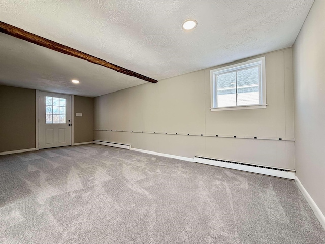 spare room featuring a baseboard heating unit, baseboards, a textured ceiling, and carpet flooring