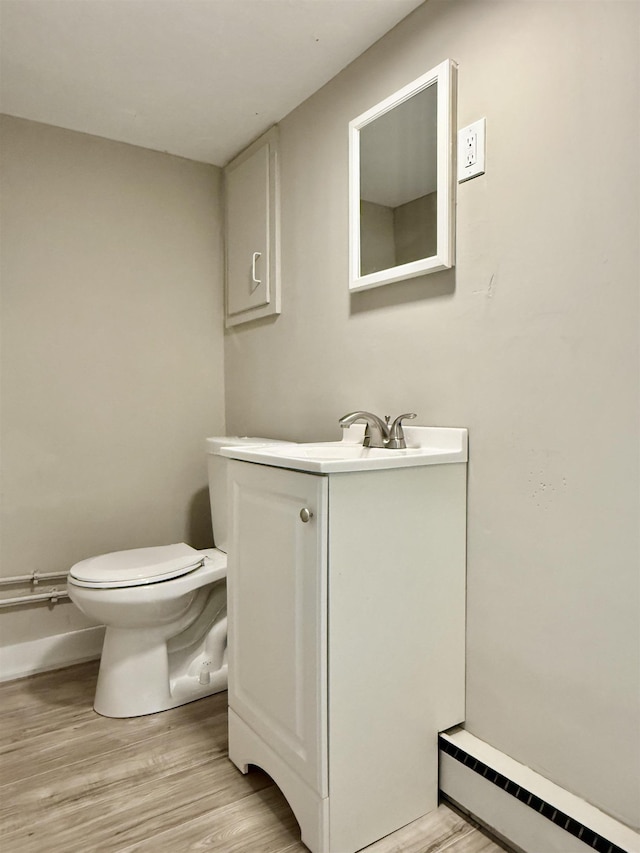 bathroom with a baseboard radiator, toilet, wood finished floors, and vanity