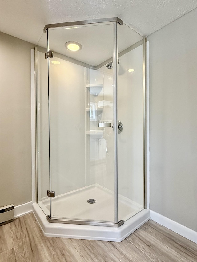 bathroom with wood finished floors, a stall shower, and baseboards