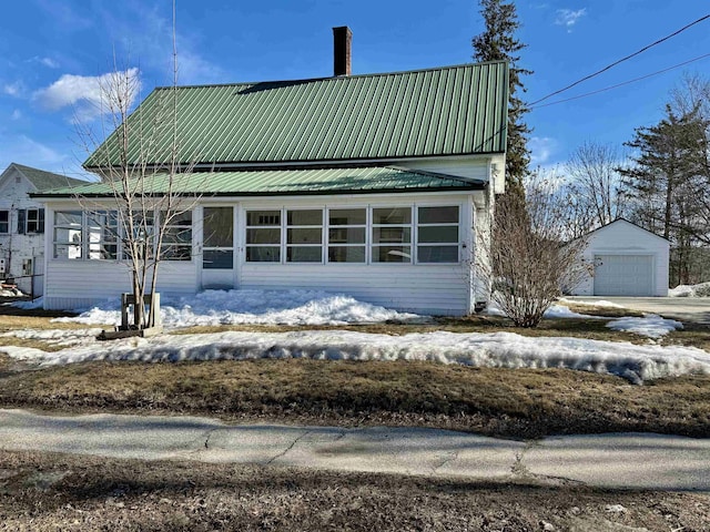 view of front of home featuring metal roof, a detached garage, an outdoor structure, and a chimney