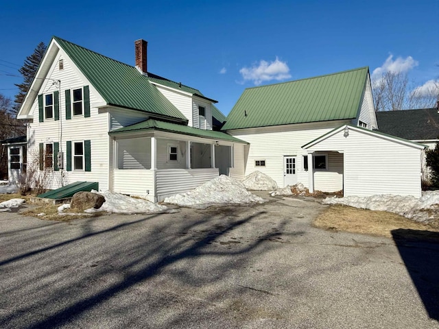 rear view of house with a chimney and metal roof