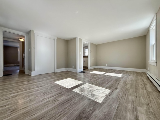 interior space featuring baseboard heating, a healthy amount of sunlight, and wood finished floors