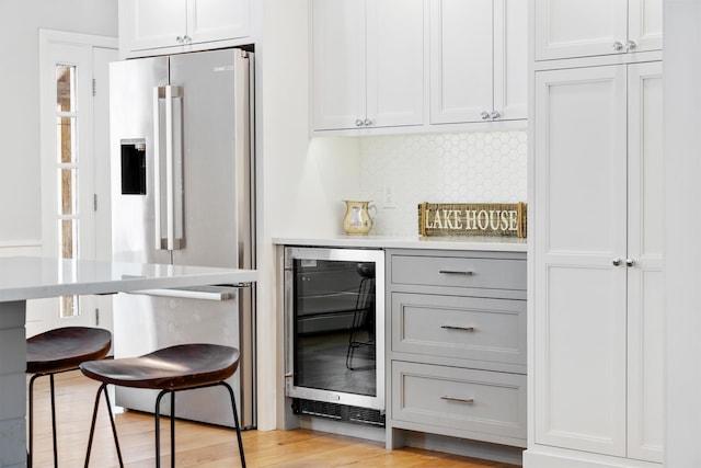 interior space featuring light wood-type flooring, beverage cooler, tasteful backsplash, and high end refrigerator