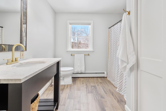 bathroom with a baseboard heating unit, toilet, wood finished floors, and vanity