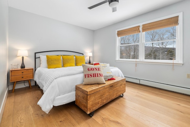 bedroom featuring a baseboard heating unit, light wood-type flooring, and ceiling fan