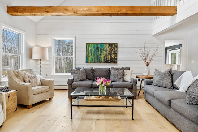 living area with a baseboard heating unit, beamed ceiling, and light wood-type flooring