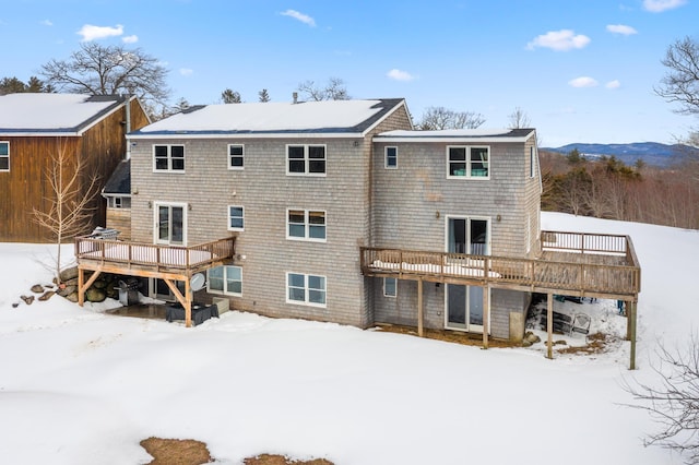 snow covered back of property featuring a deck