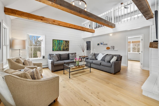 living room featuring light wood-type flooring, beam ceiling, and a baseboard heating unit