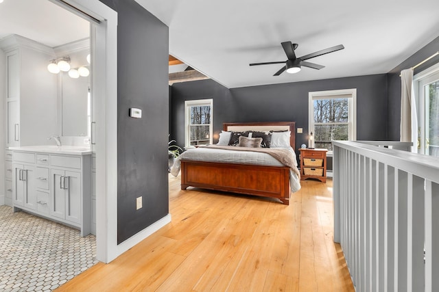 bedroom featuring a sink, ensuite bath, a ceiling fan, and light wood finished floors