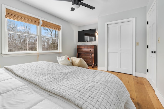 bedroom featuring a closet, baseboards, a ceiling fan, and light wood finished floors