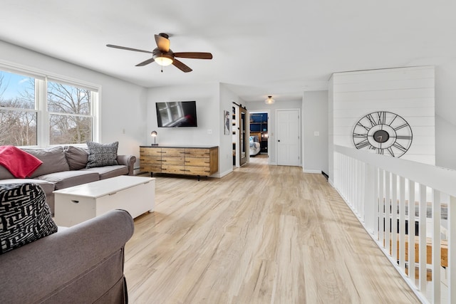 living area featuring light wood-style flooring, a ceiling fan, and baseboards