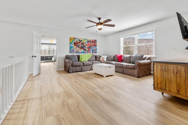 living room featuring a ceiling fan, baseboards, and light wood-type flooring