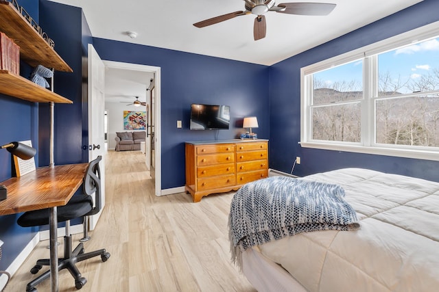 bedroom featuring baseboard heating, baseboards, light wood finished floors, and ceiling fan