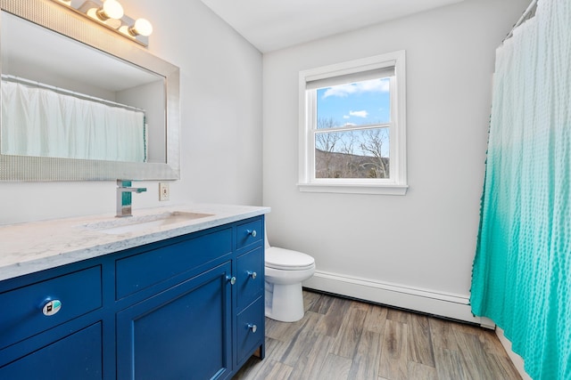 bathroom featuring a baseboard radiator, toilet, wood finished floors, and vanity