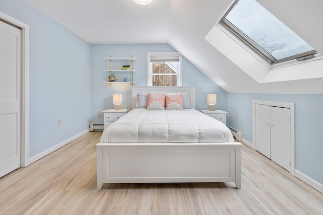 bedroom featuring lofted ceiling with skylight, wood finished floors, baseboards, and a baseboard radiator