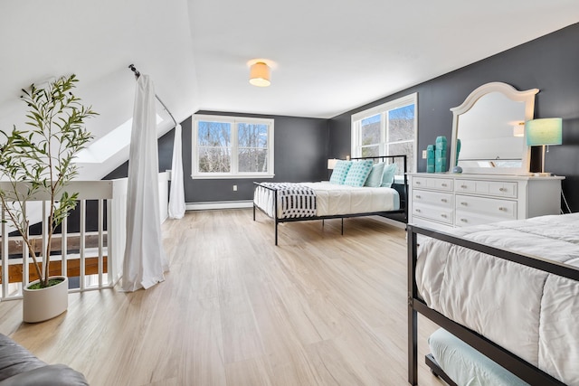 bedroom featuring vaulted ceiling, light wood-type flooring, and a baseboard radiator