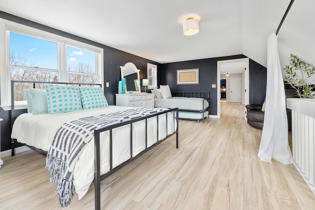 bedroom featuring vaulted ceiling, baseboards, and light wood-type flooring