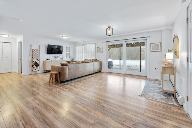 living area with light wood-style flooring, a baseboard heating unit, and baseboards