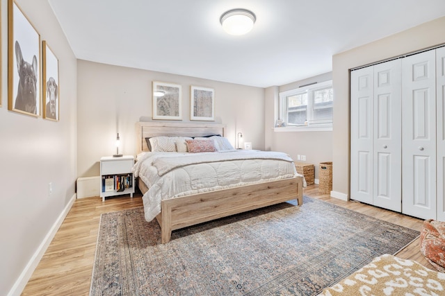 bedroom with a closet, baseboards, and light wood finished floors