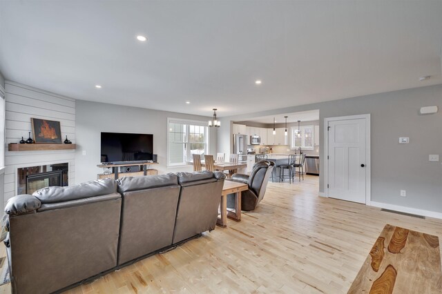 living room with recessed lighting, a fireplace, baseboards, and light wood finished floors