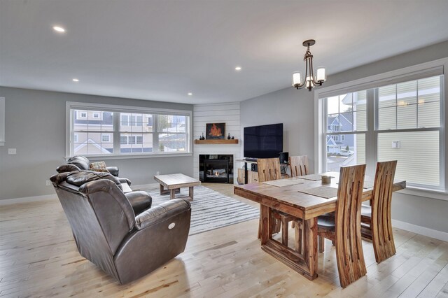 living room featuring a glass covered fireplace, plenty of natural light, baseboards, and light wood finished floors