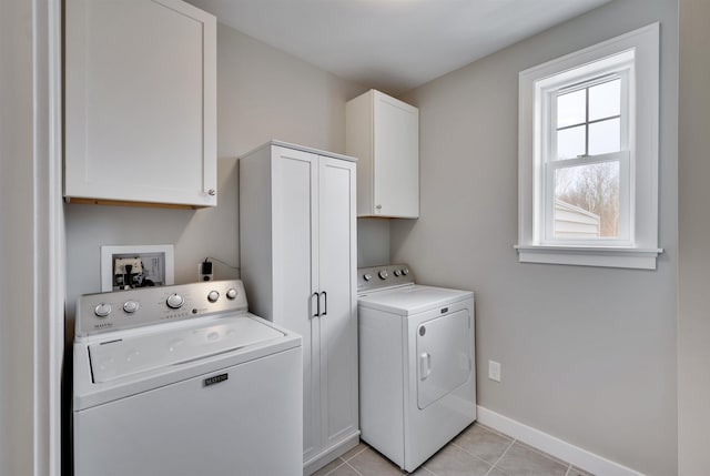 laundry area with light tile patterned flooring, cabinet space, baseboards, and washer and clothes dryer