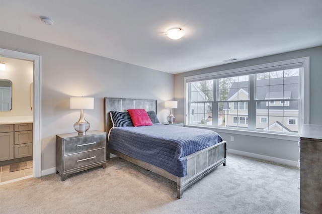 bedroom featuring visible vents, light colored carpet, ensuite bath, and baseboards