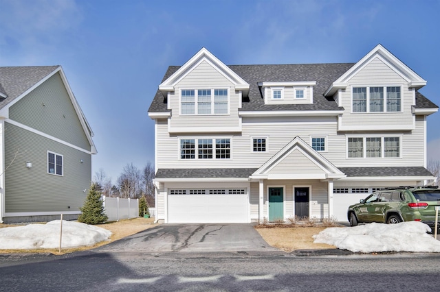 view of front of house with driveway, an attached garage, roof with shingles, and fence