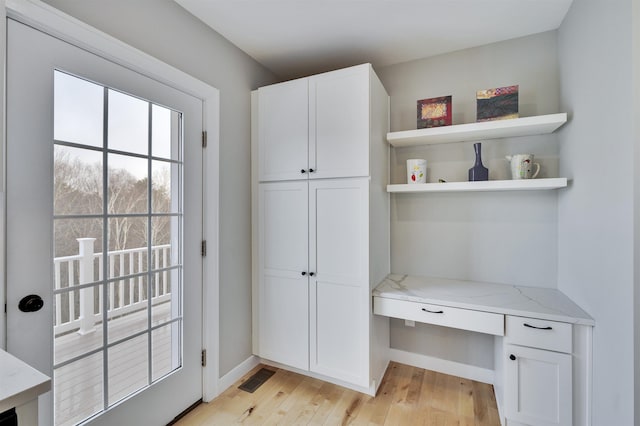 interior space featuring visible vents, baseboards, light wood-style flooring, and built in study area