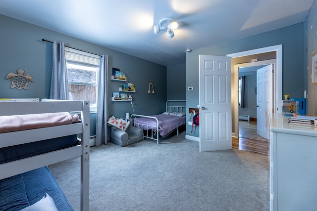 bedroom featuring a baseboard radiator, baseboards, and light colored carpet