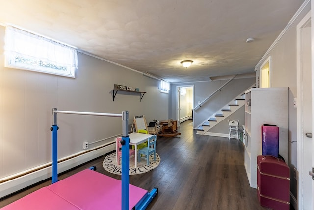 workout room with a baseboard heating unit, crown molding, and hardwood / wood-style flooring