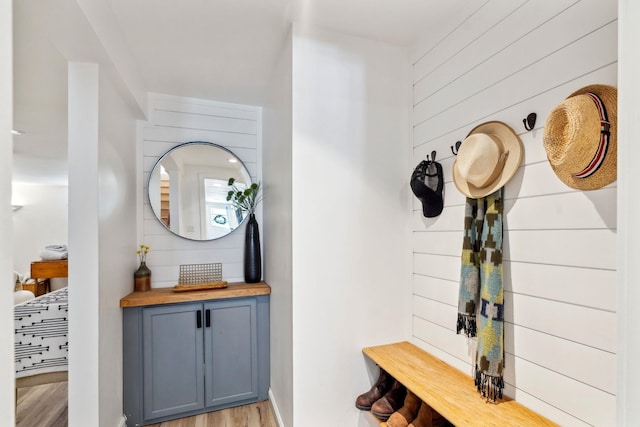 mudroom with light wood-style flooring and wood walls