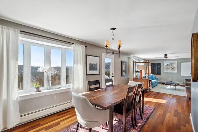 dining area featuring ceiling fan with notable chandelier, baseboard heating, and hardwood / wood-style flooring