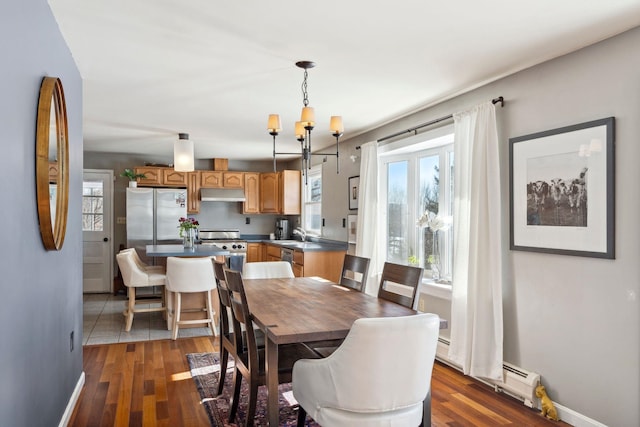 dining room with an inviting chandelier, dark wood-type flooring, and baseboards