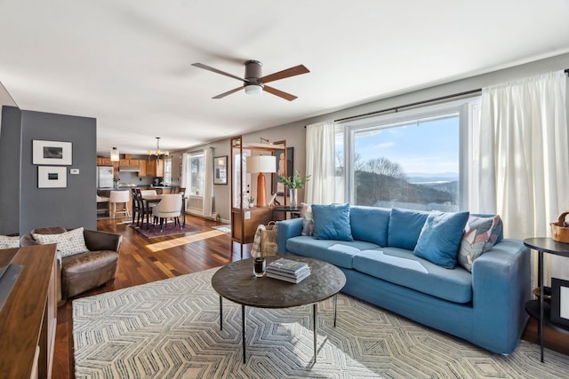 living area featuring ceiling fan with notable chandelier and wood finished floors