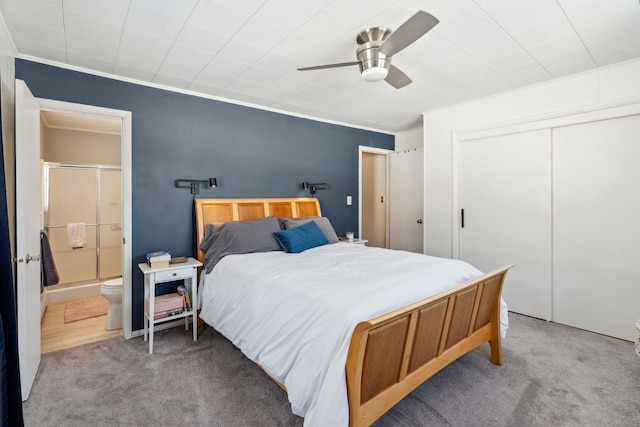 bedroom featuring a ceiling fan, carpet, ensuite bath, ornamental molding, and a closet