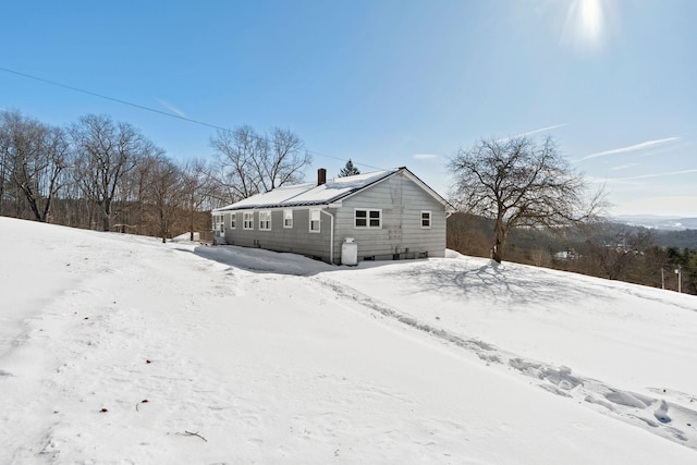 view of snowy exterior featuring a garage and a chimney