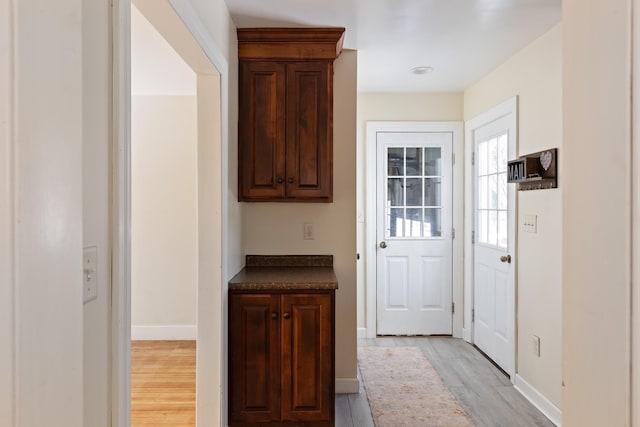 doorway to outside with baseboards and light wood finished floors